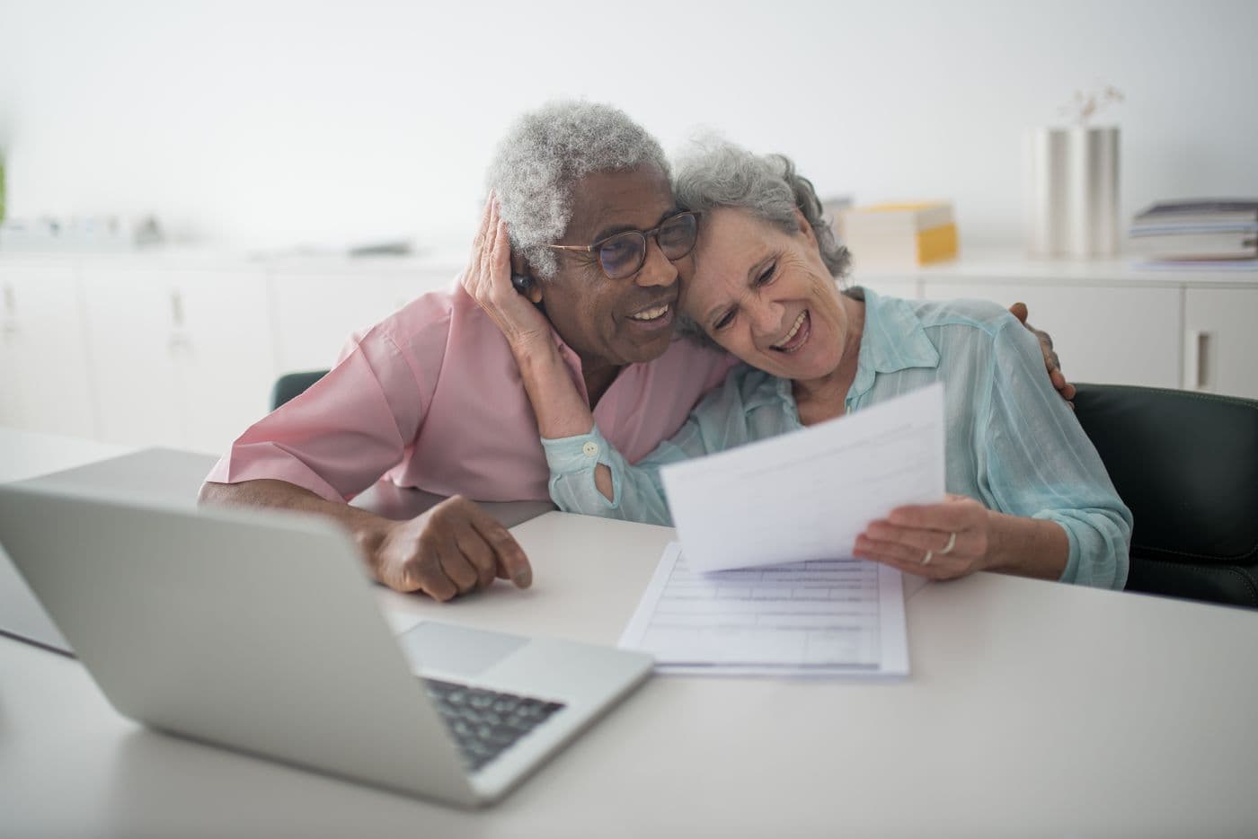 Un couple souriant consulte ses documents administratifs à la maison.
