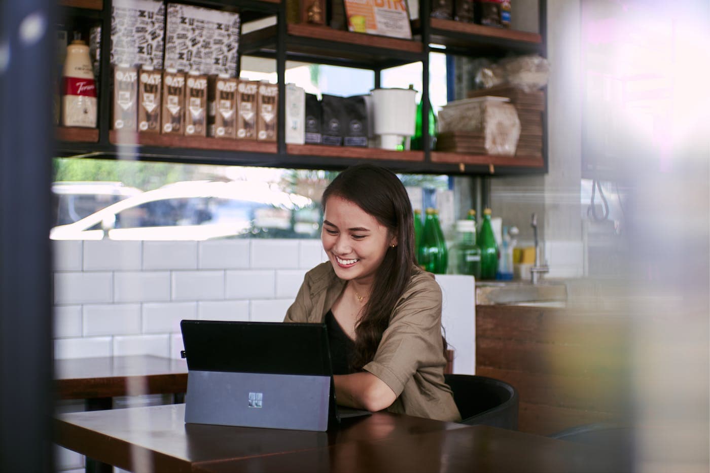 Une entrepreneuse souriante travaille sur son ordinateur portable dans son commerce.