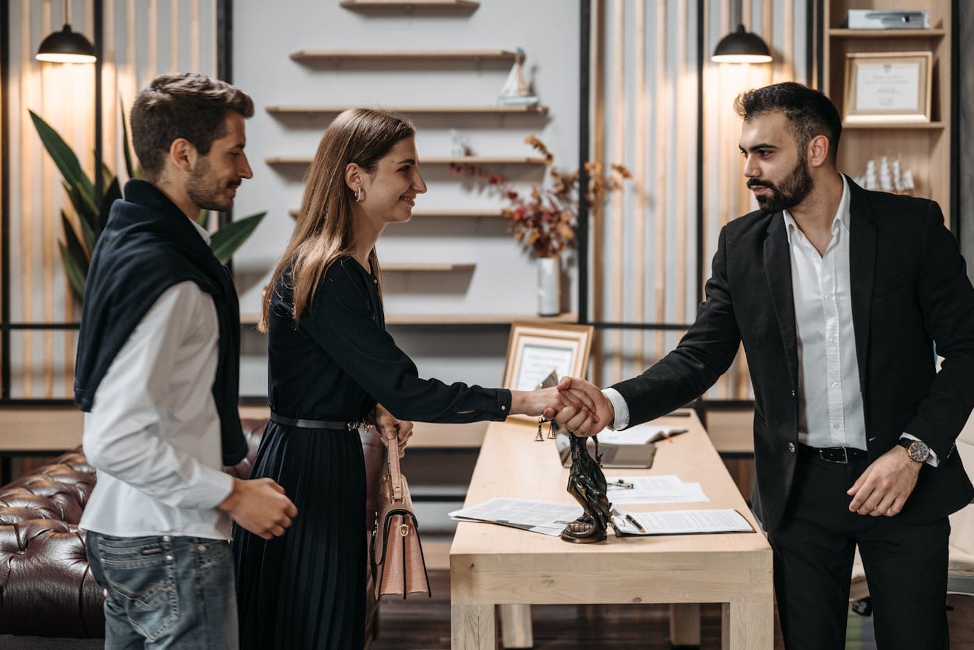 Une conseillère sert la main de ses clients professionnels lors d'un rendez-vous.
